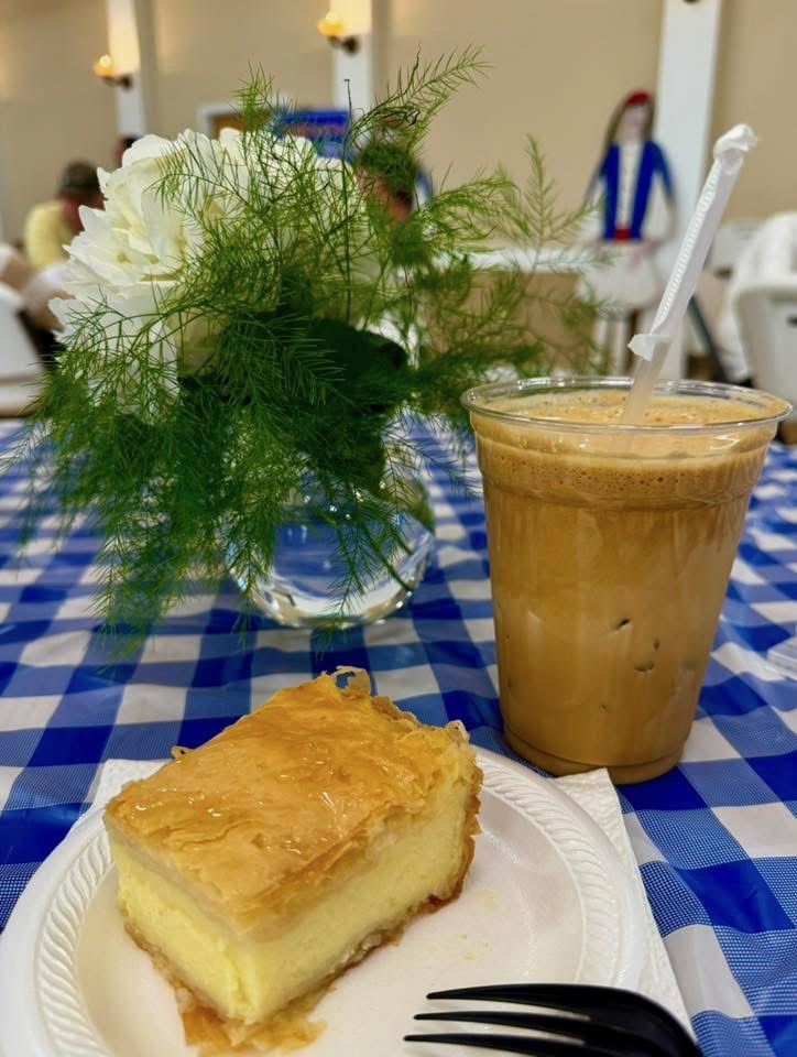 A slice of galaktoboureko and an iced frappe on a blue gingham tablecloth